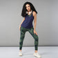 A woman with curly hair wears headphones, a Tie & Dye Bra T shirt, green leggings, and white sneakers as she poses confidently.
