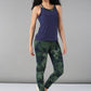 Woman wears a Tie & Dye Bra T shirt and green tie-dye leggings, standing against a plain gray background.