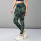 A woman models the Tie & Dye Leggings in green, made from stretchy fabric, paired with a navy crop top and white sneakers against a gray background—ideal for updating your workout wardrobe.