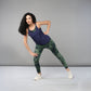 A woman in athletic wear stretches sideways against a plain grey background, highlighting Tie & Dye Leggings that bring vibrant color and flair to her workout wardrobe.