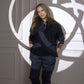 A woman in the Accented Set, featuring a batwing sleeve shirt, stands against a wall with artistic shadows behind her.