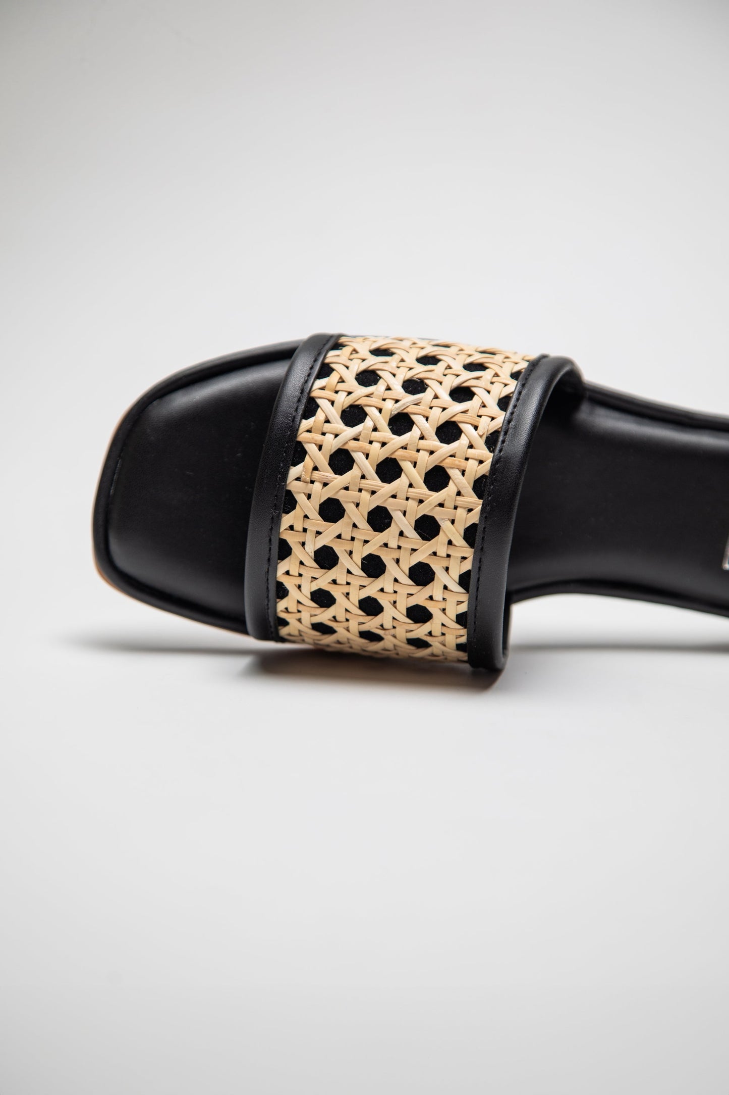 Close-up of black and beige woven sandals for women with open toe design by Stylera