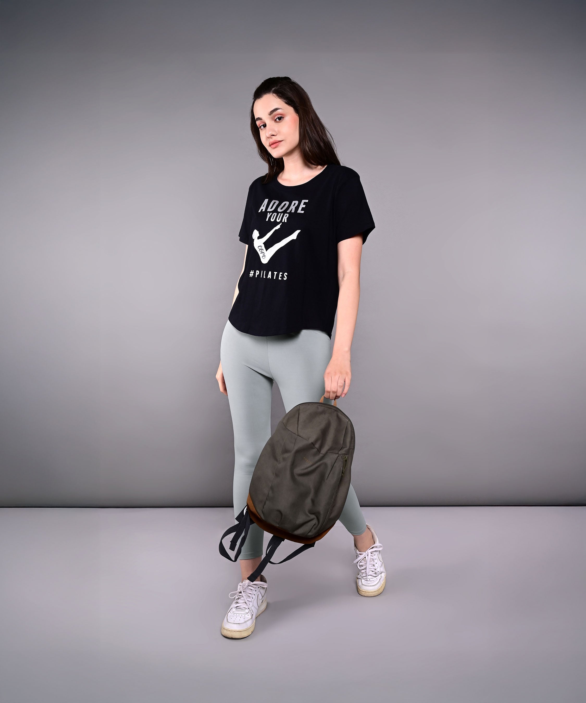 Woman wearing Adore Your Core printed tee with gray leggings and a backpack, showcasing activewear style