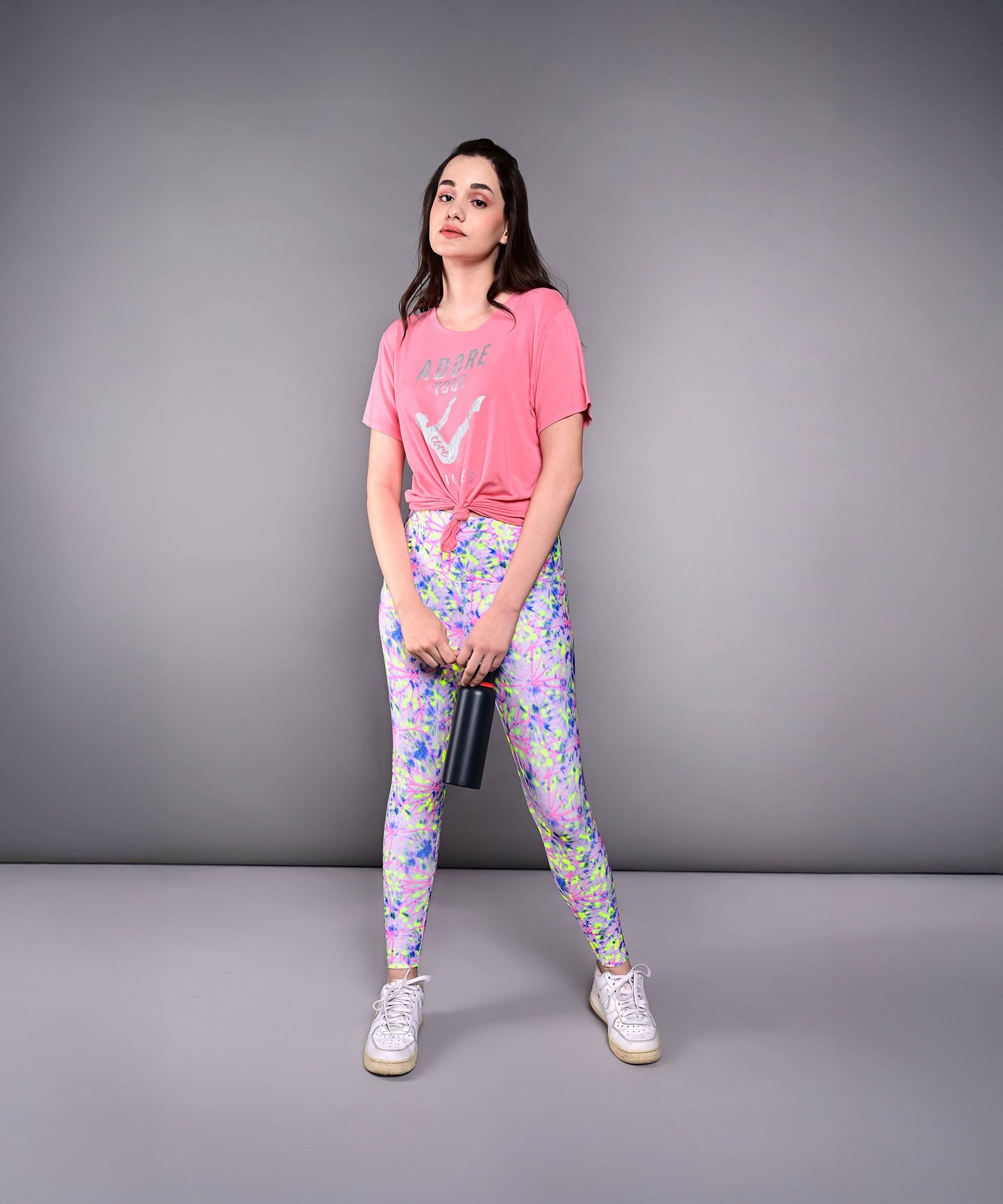 Model wearing Adore Your Core printed tee with colorful leggings, standing confidently in studio setting