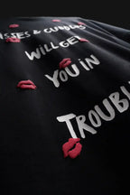 Black shirt with white text and red lip prints on a dark background