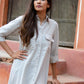 Model wearing an ash grey midi shirt dress with button details and a chest pocket in a rustic setting