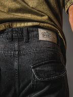 Man wearing black baggy jeans with knee design and chunky sneakers.