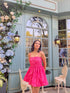 Model wearing a hot pink Barbie balloon dress with thin straps posed by pastel cafe window