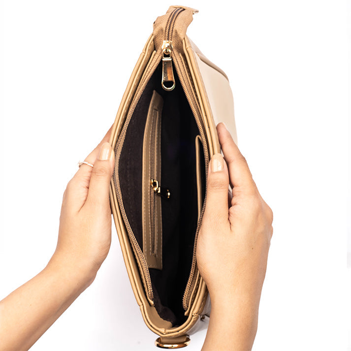 Hands holding a beige crossbody purse showing spacious interior and organized pockets