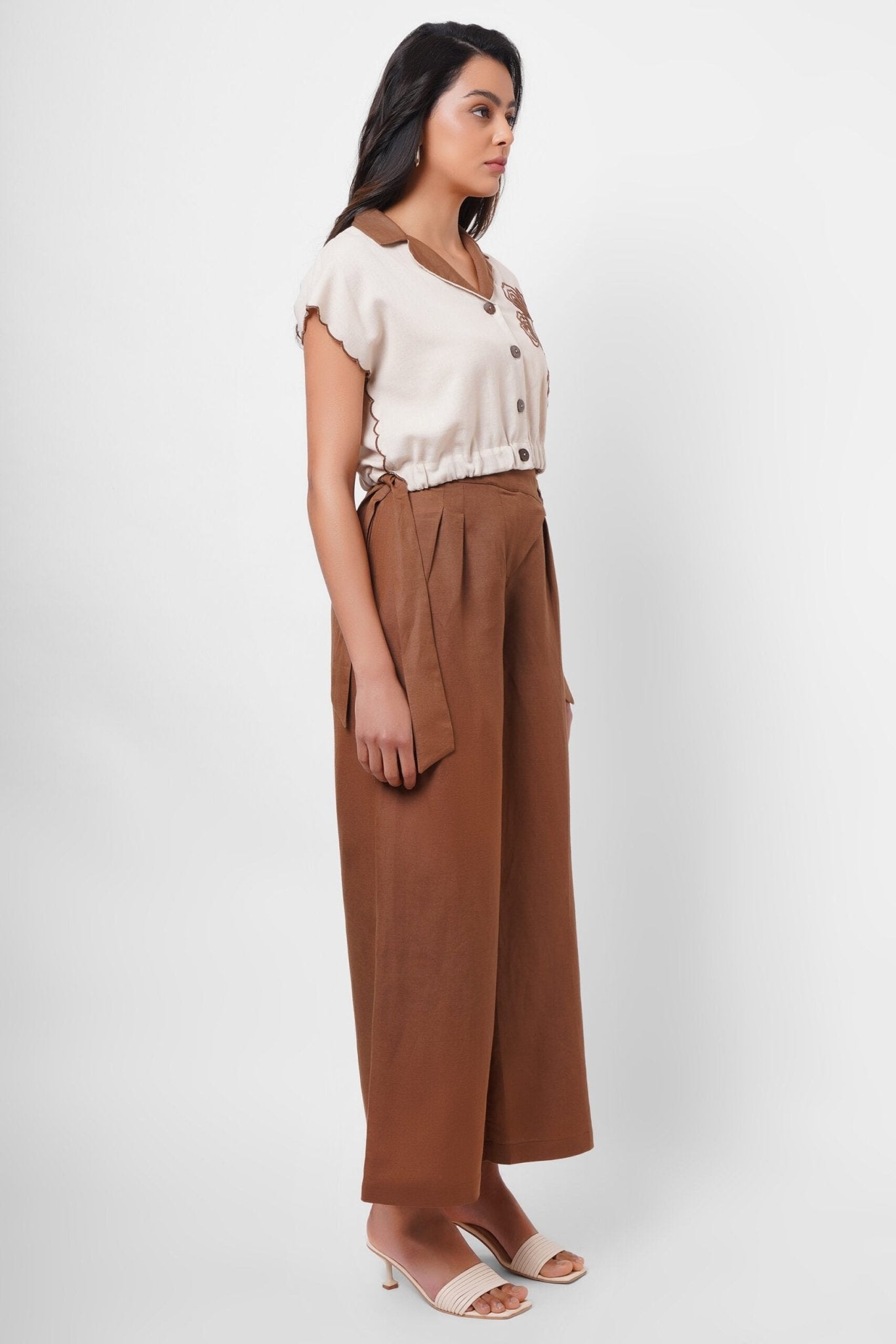 Side view of a woman wearing Western Era beige embroidered linen top with brown wide-leg pants
