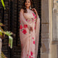 Model wearing a beige floral chiffon saree adorned with vibrant pink flowers, styled elegantly outdoors