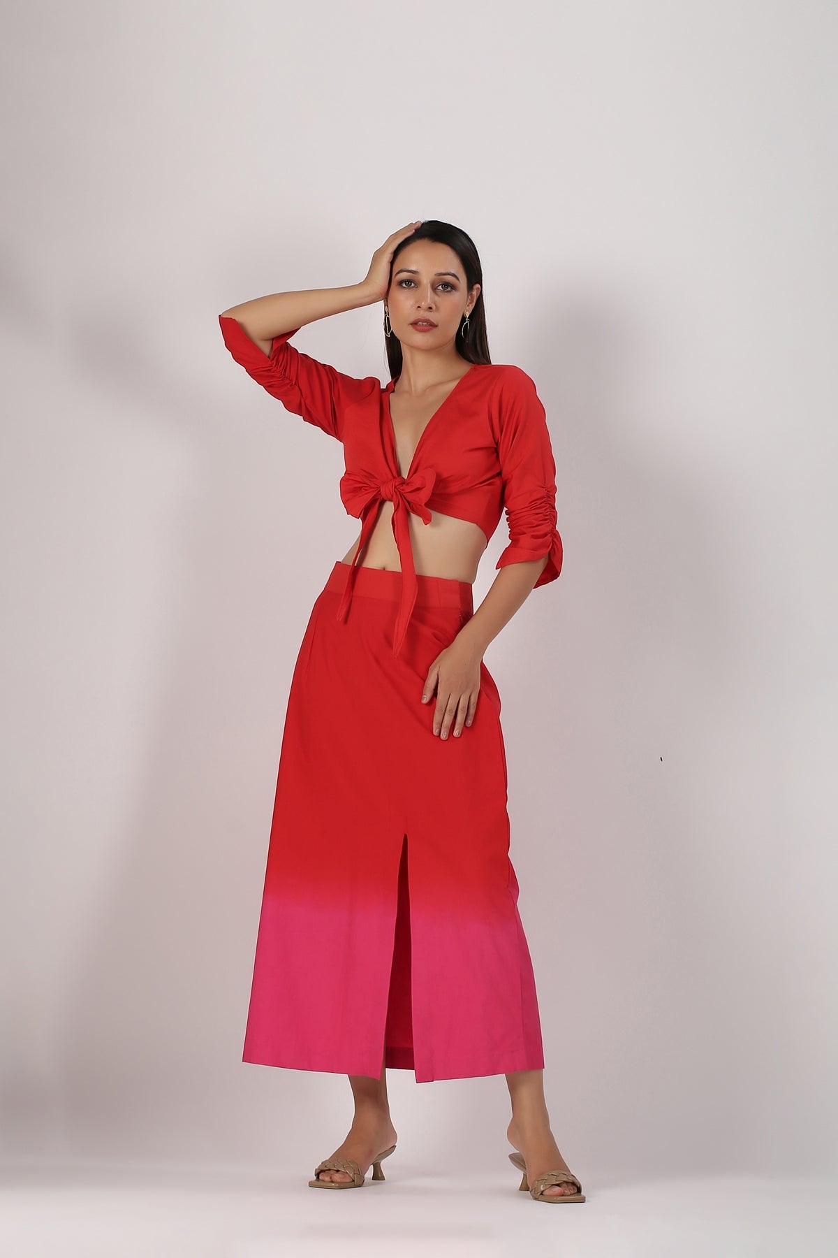 Stylera beach wear model wearing a stylish ombre skirt and top set red to pink tie front crop top with high slit skirt