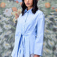 Stylera model wearing unique casual light blue shirt for women with tie front waist and long sleeves
