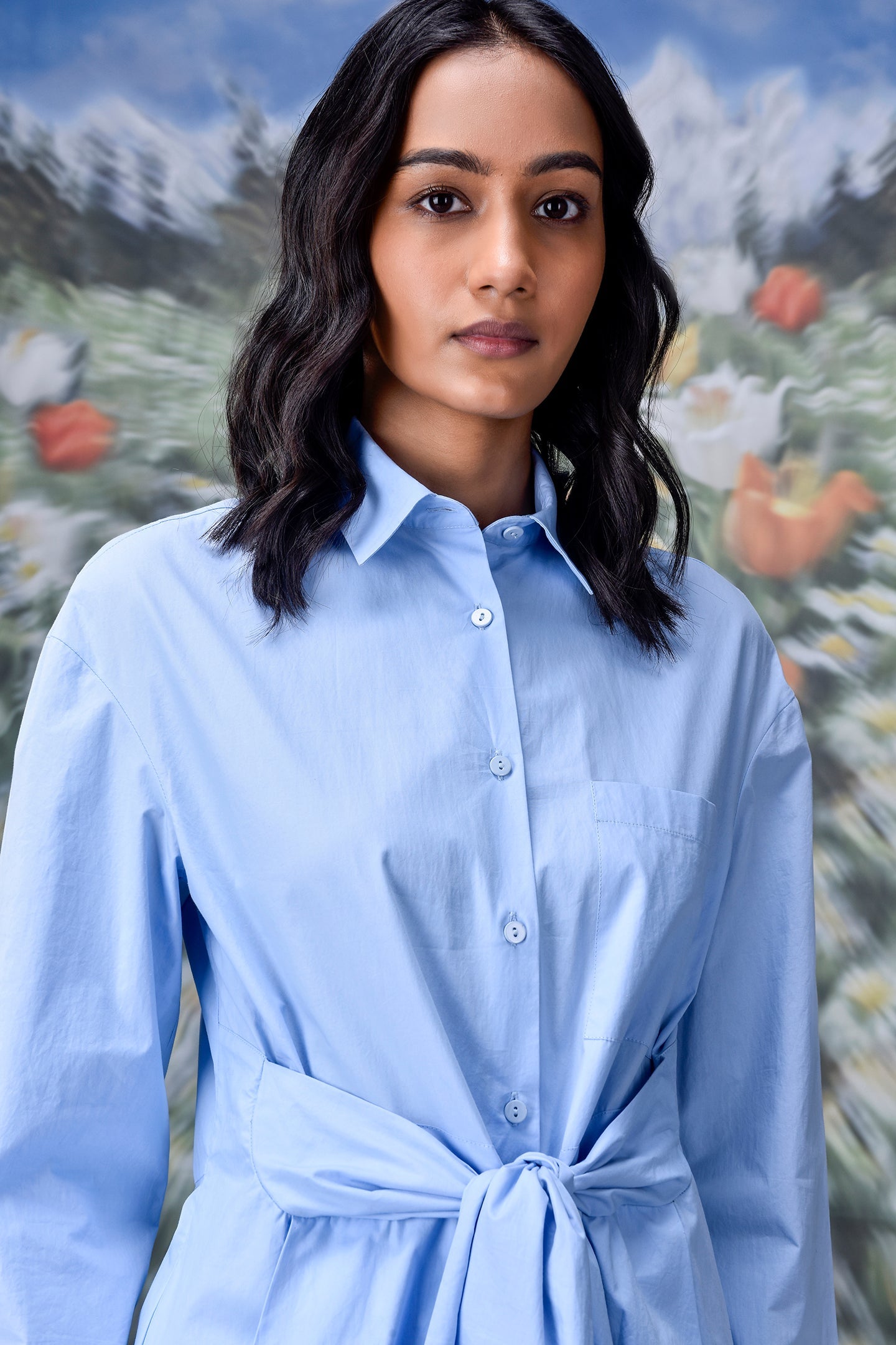 Model wearing Stylera unique casual light blue shirt for women with waist tie and button front
