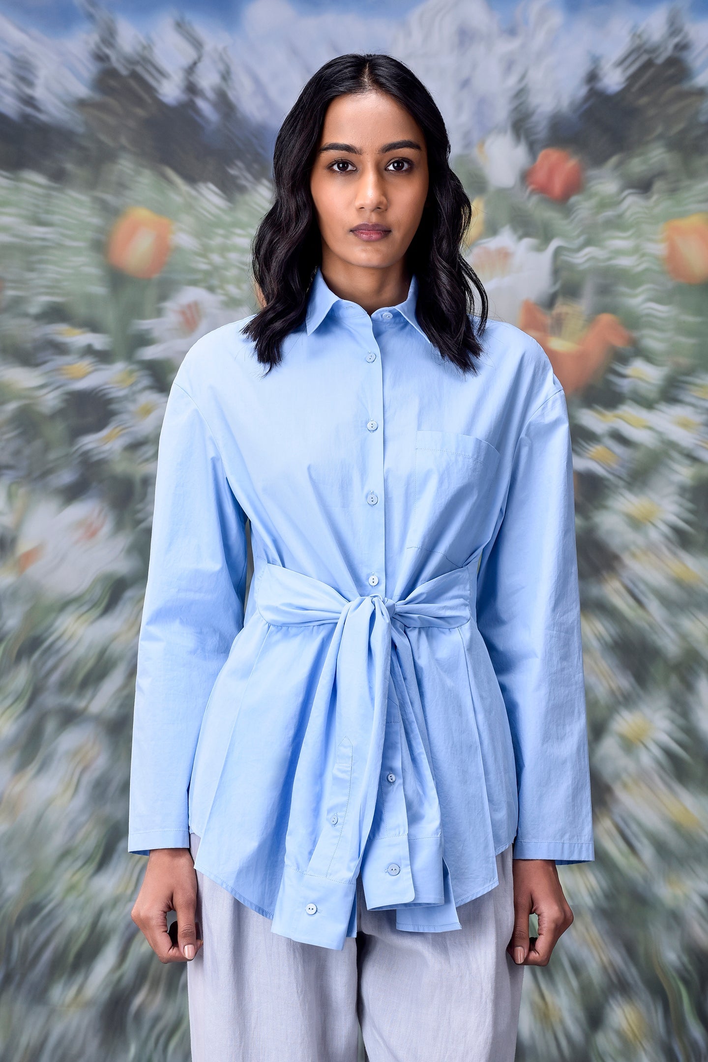 Stylera model wearing unique casual light blue shirt for women with tie waist and long sleeves