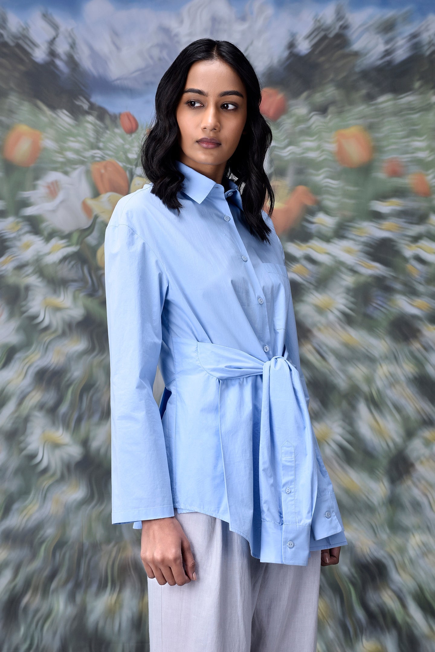 Stylera model wearing unique casual light blue shirt for women collared button down with waist tie
