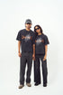 Male and female models wearing Stylera black acid wash oversized t-shirt with claw graphic paired with black pants