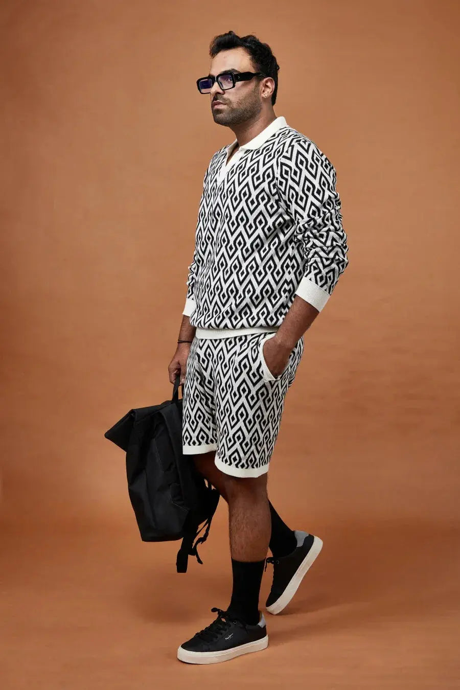 Trendy black and white patterned shorts men paired with a matching sweatshirt and stylish sneakers