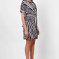 Stylera black and white wrap dress with geometric stripes worn with black high heel sandals