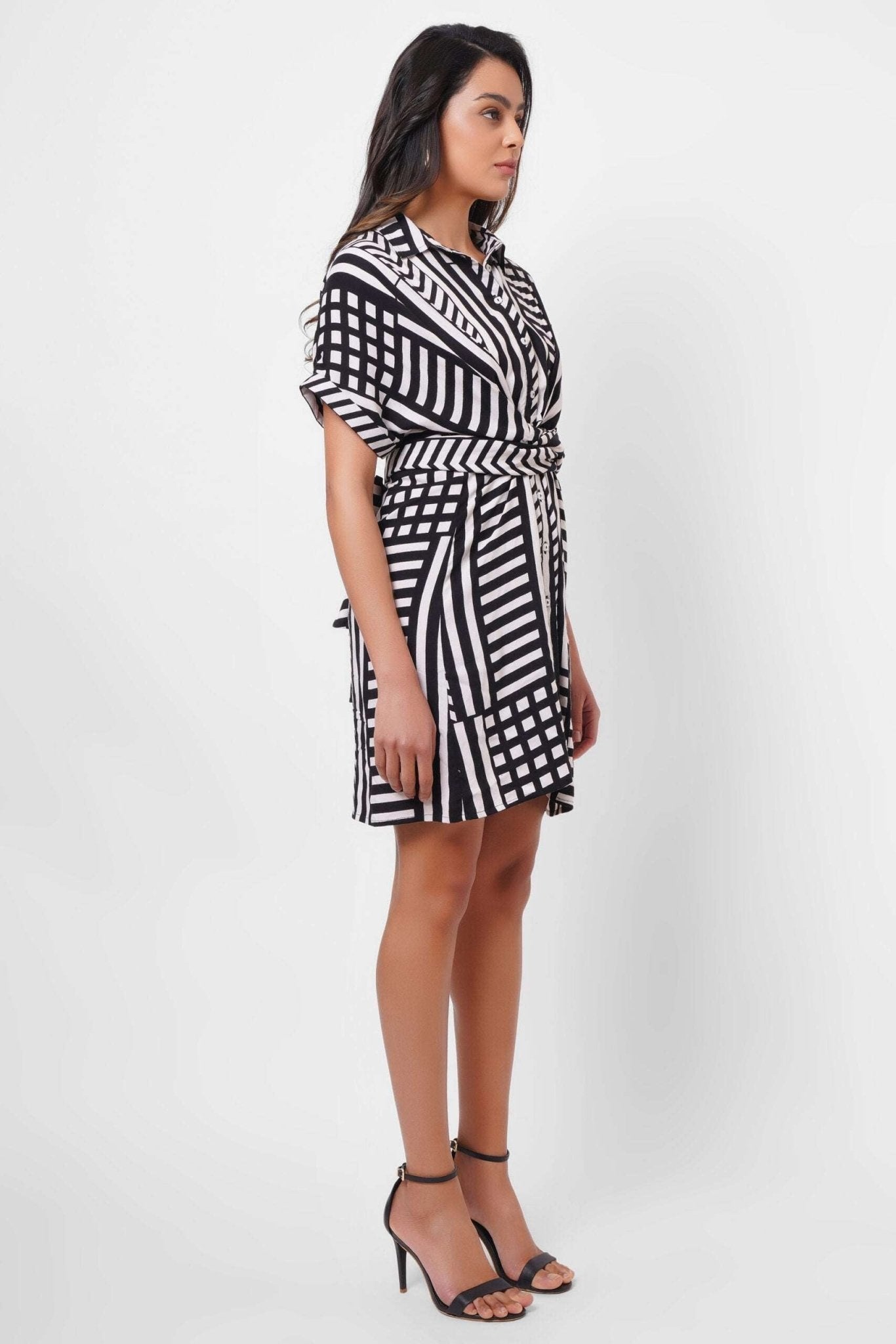 Stylera black and white wrap dress with geometric stripes worn with black high heel sandals
