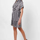 Stylera black and white wrap dress with geometric stripes worn by woman with black heels