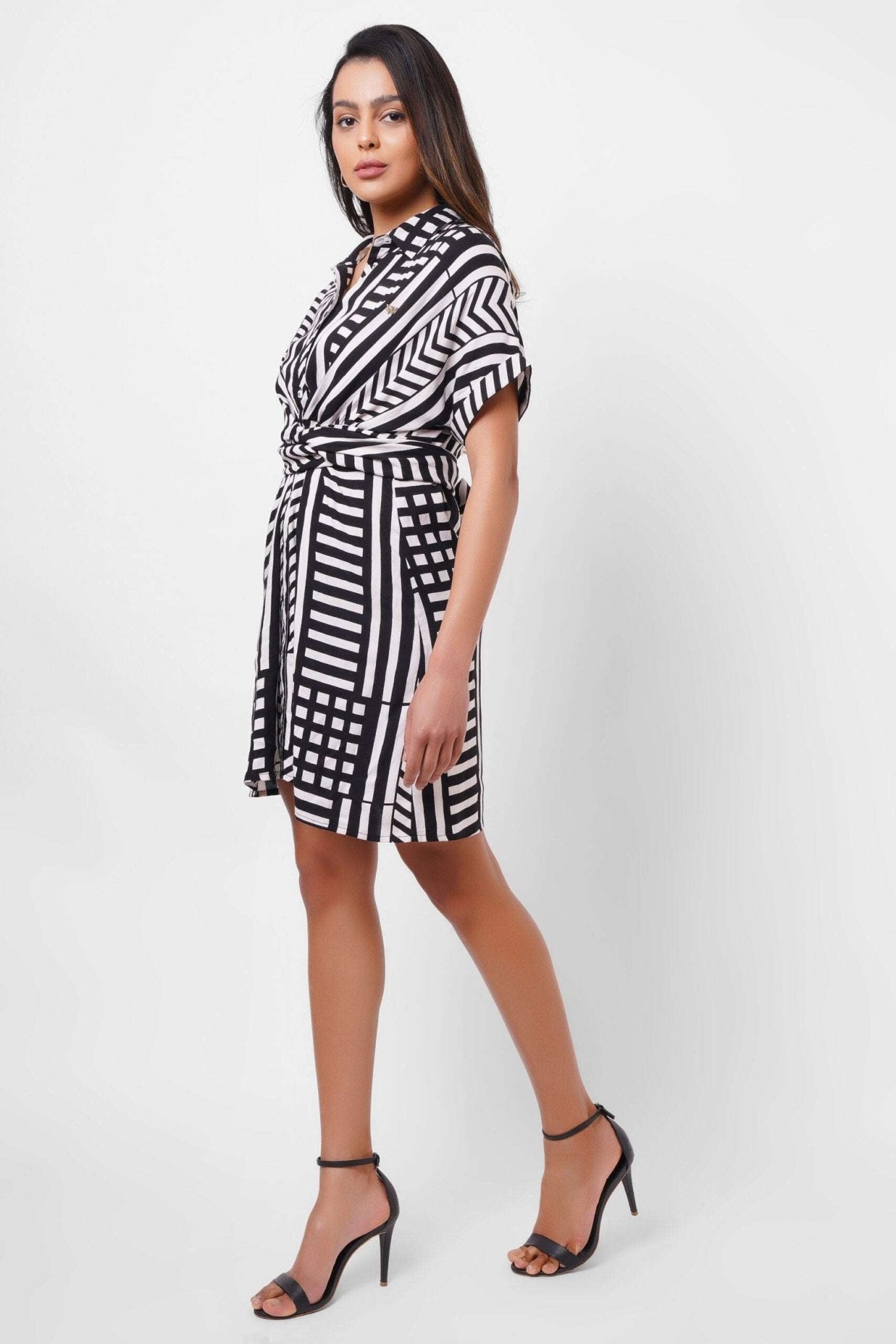 Stylera black and white wrap dress with geometric stripes worn by woman with black heels