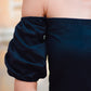Close-up of black off shoulder short dress featuring puff sleeves for a stylish look