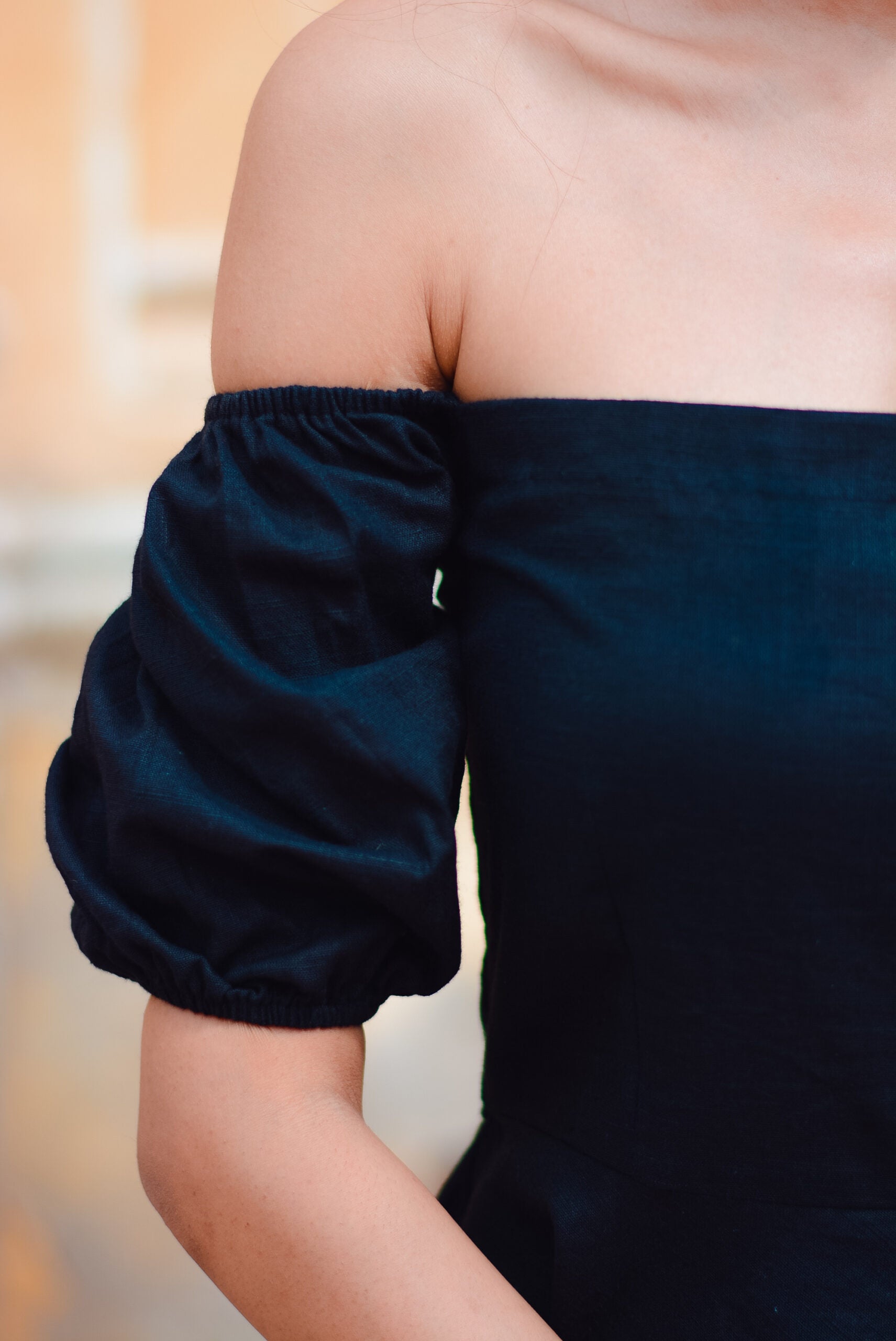 Close-up of black off shoulder short dress featuring puff sleeves for a stylish look