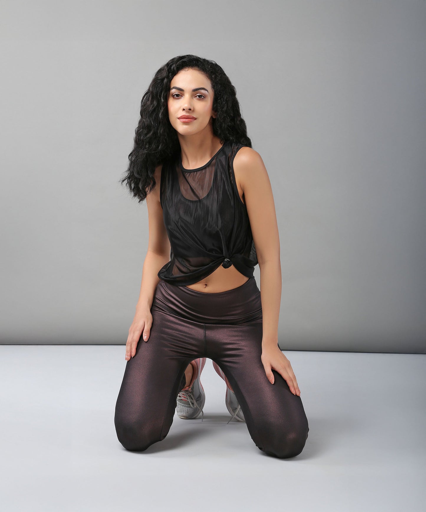 Model wearing a stylish black sheer top for women paired with sleek leggings, showcasing a trendy active look