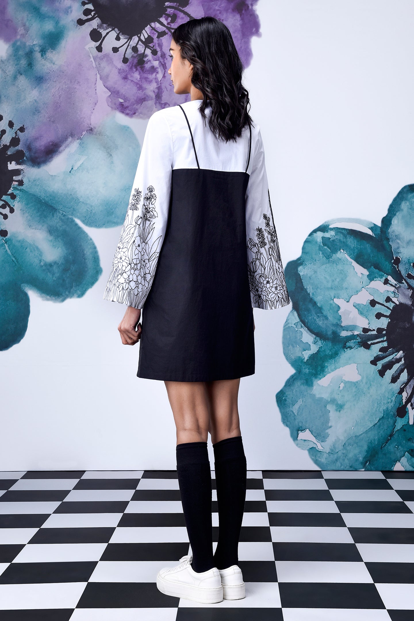 Back view of Stylera black white layered dress with embroidered white sleeves knee socks and platform sneakers