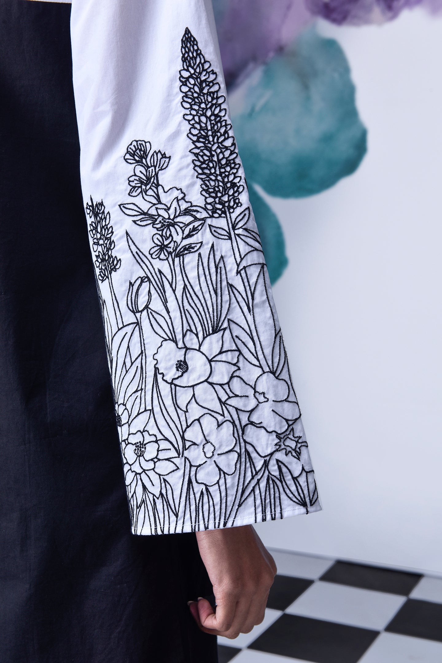Stylera black white layered dress close up of embroidered white sleeve and black dress body on check floor