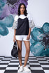 Model wearing Stylera black white layered top over patterned white tee with white shorts