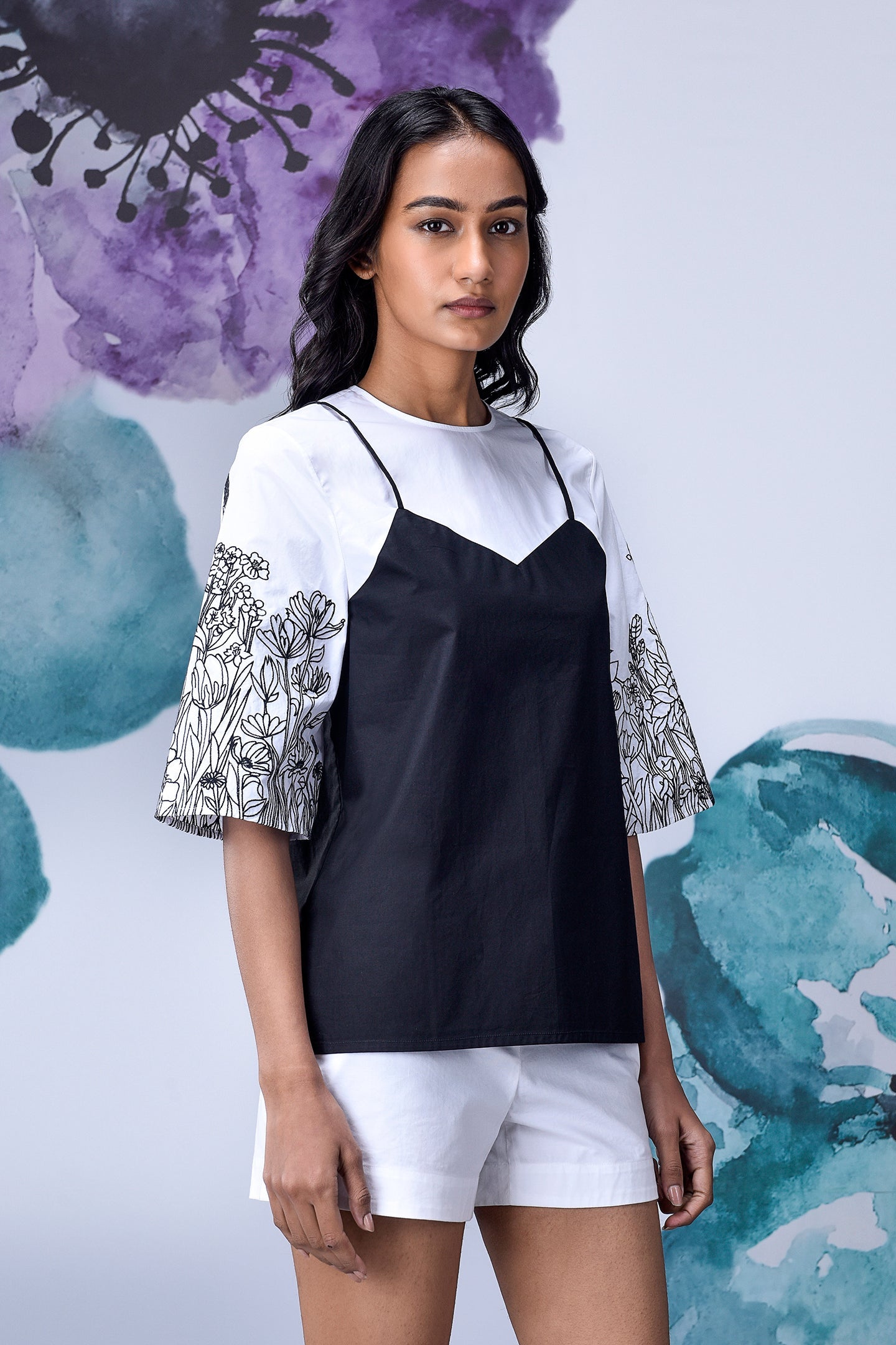 Model wearing Stylera black white layered top with floral elbow sleeves and white shorts