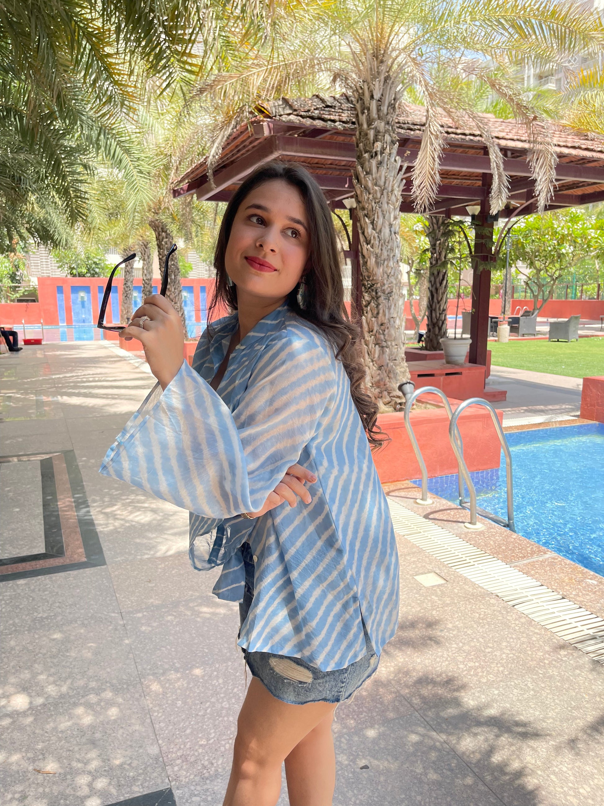 Stylish blue lehriya print shirt for women, paired with denim shorts, perfect for casual outings