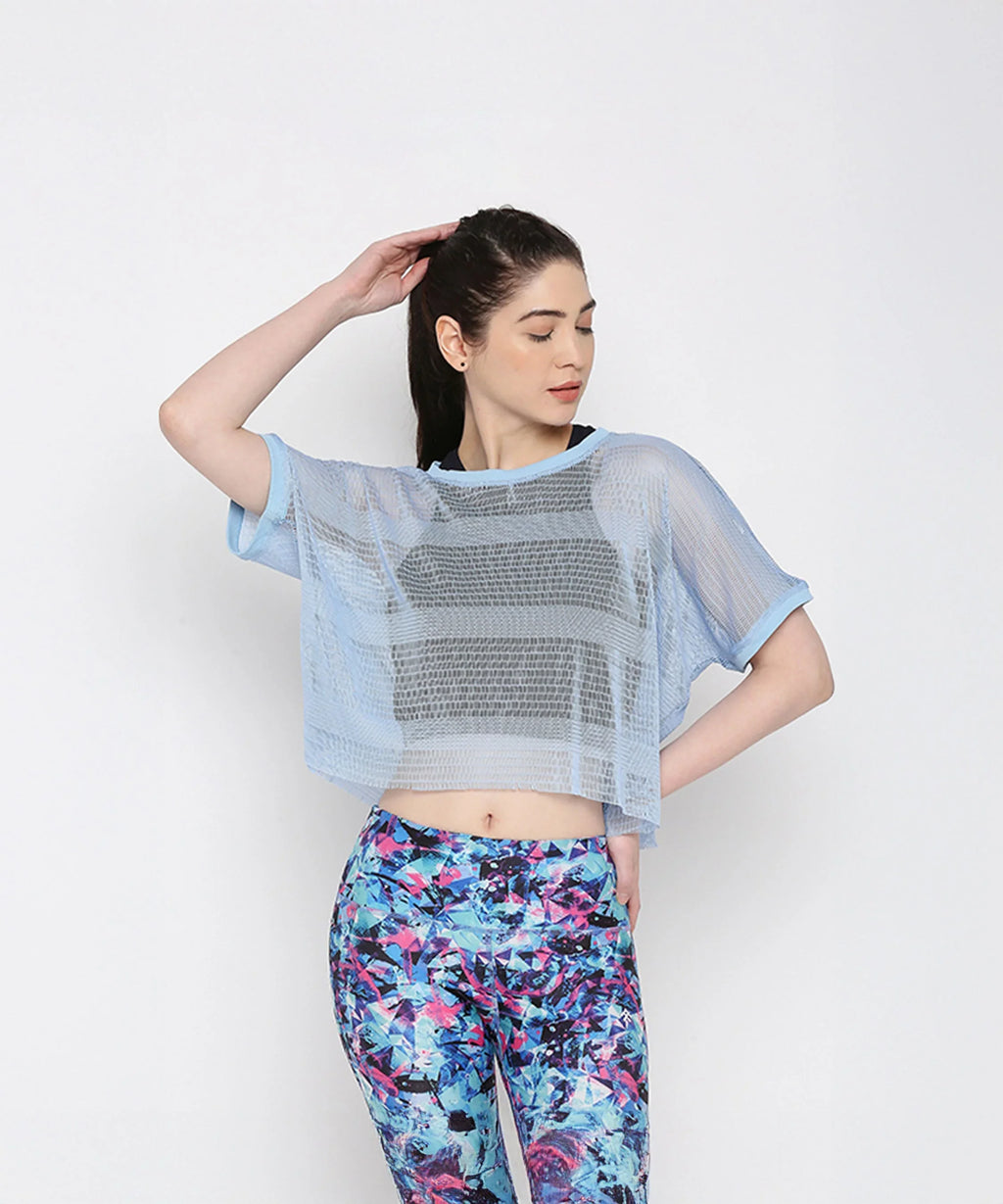 Blue netted top for women layered over a black sports bra, styled with colorful workout leggings