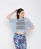 Blue netted top for women layered over a black sports bra, styled with colorful workout leggings