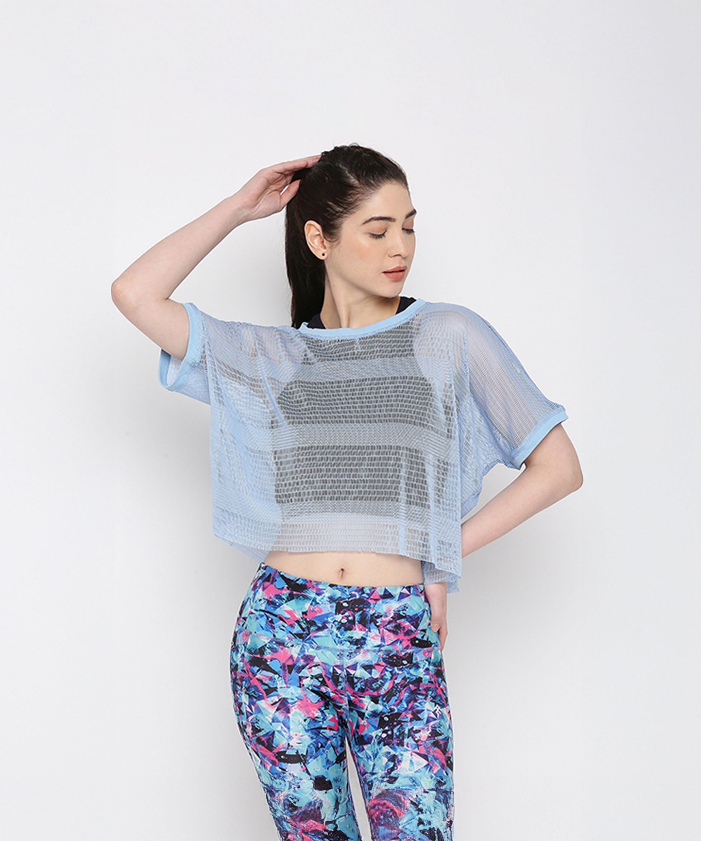 Blue netted top for women layered over a black sports bra, styled with colorful workout leggings