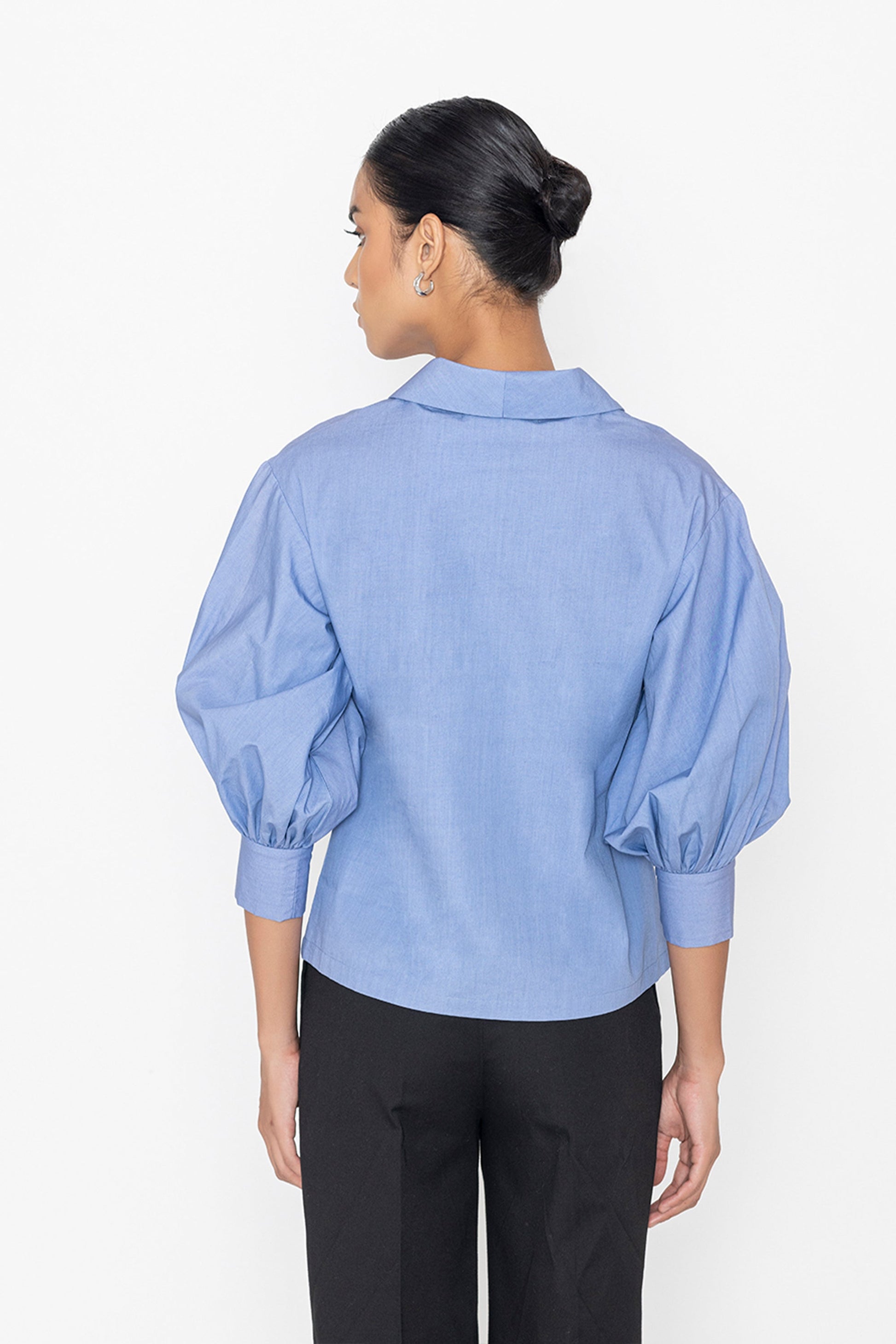Stylera blue v-neck blouse with puff sleeves shown from the back on a female model