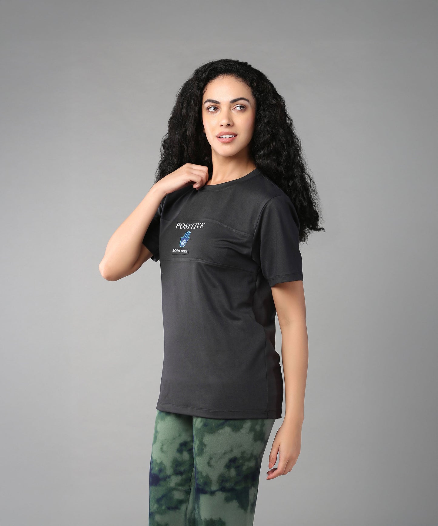 Stylera Positive Graphic Tee in Black, ideal body positivity clothing for women, paired with green patterned leggings