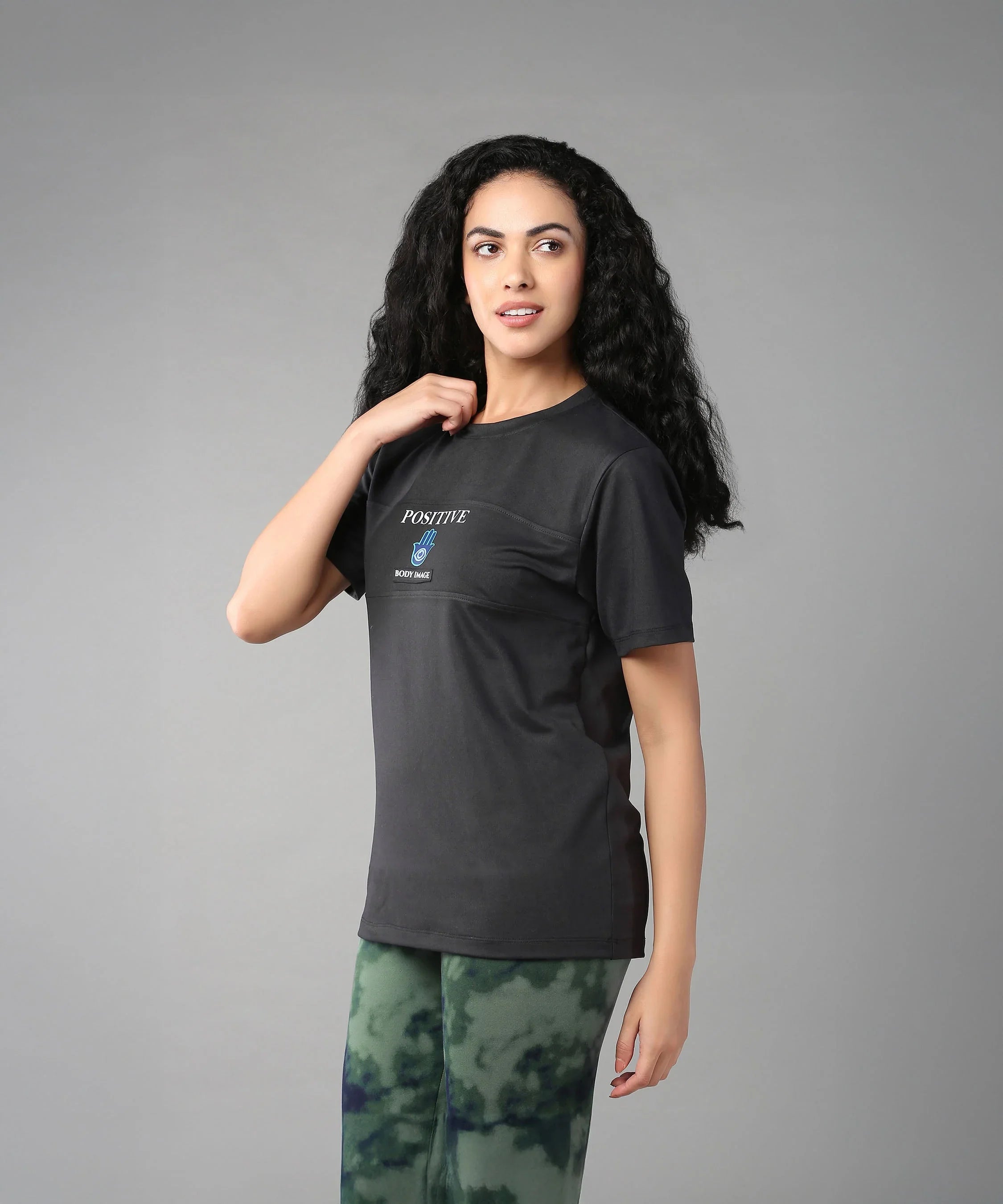 Stylera Positive Graphic Tee in Black, ideal body positivity clothing for women, paired with green patterned leggings