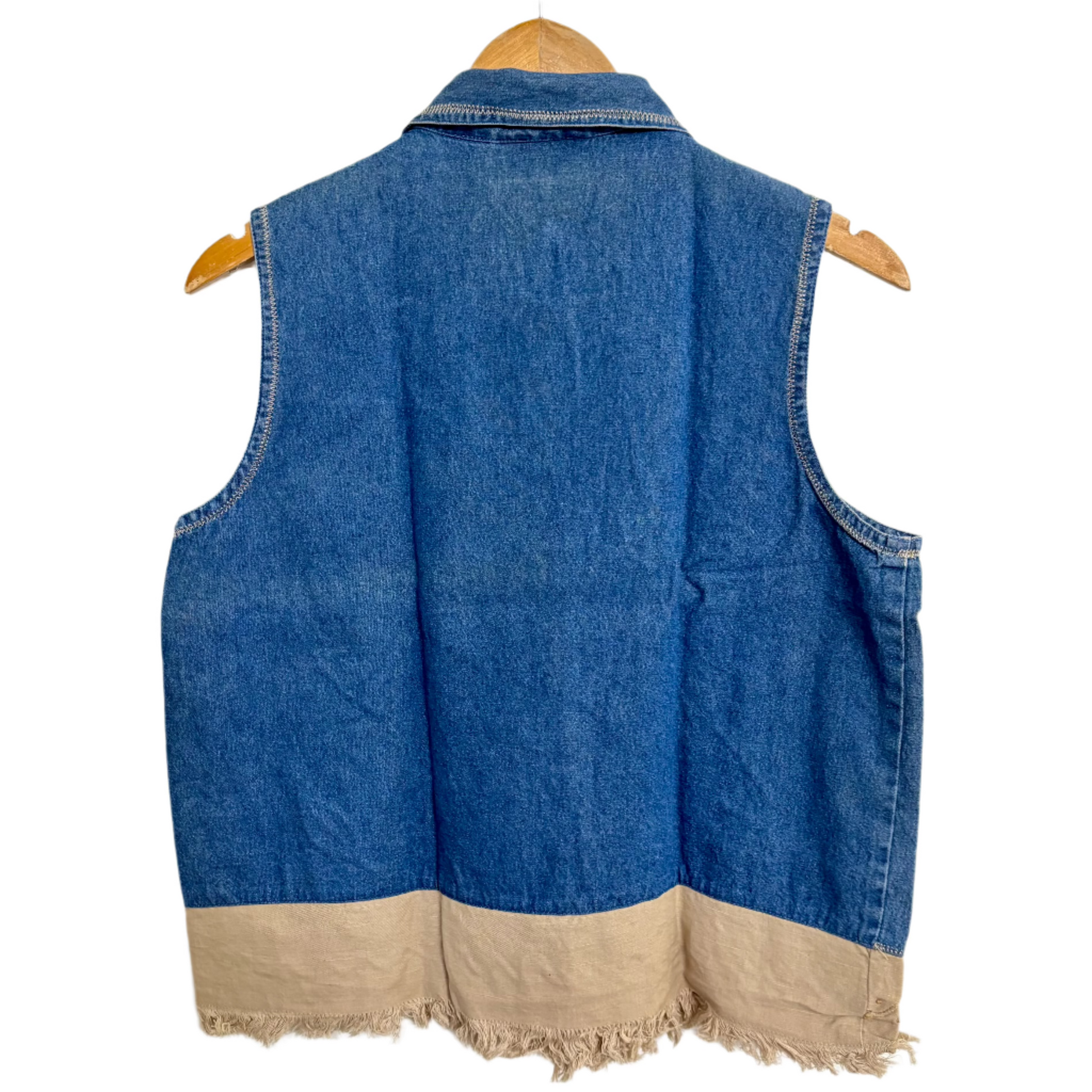 Embroidered denim vest for women back view showing plain blue back and tan frayed hem on wooden hanger