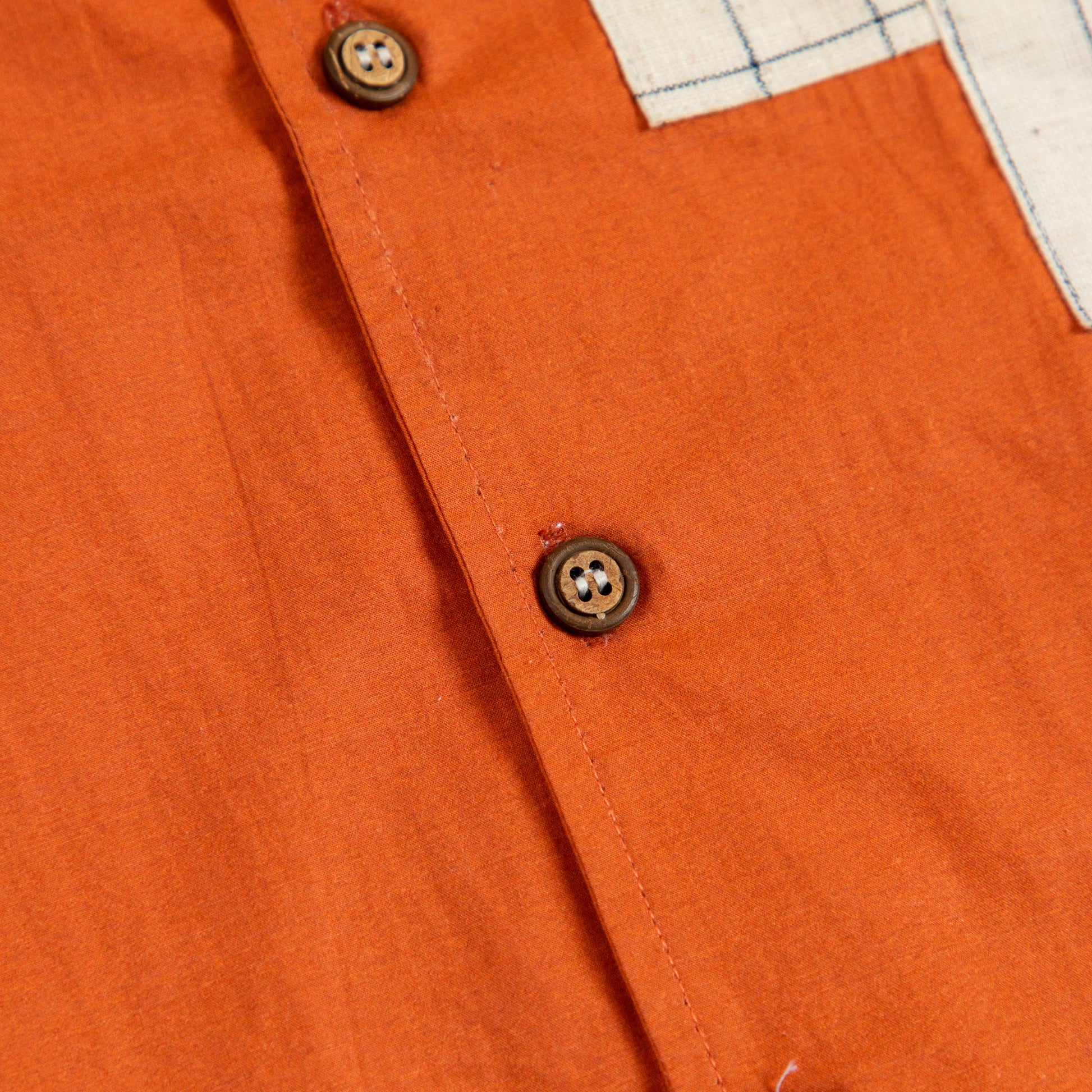 Close-up of Stylera boho charm short sleeve shirt in vibrant orange with wooden buttons