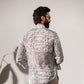 Back view of a man wearing a boho white silk shirt for men with intricate patterns