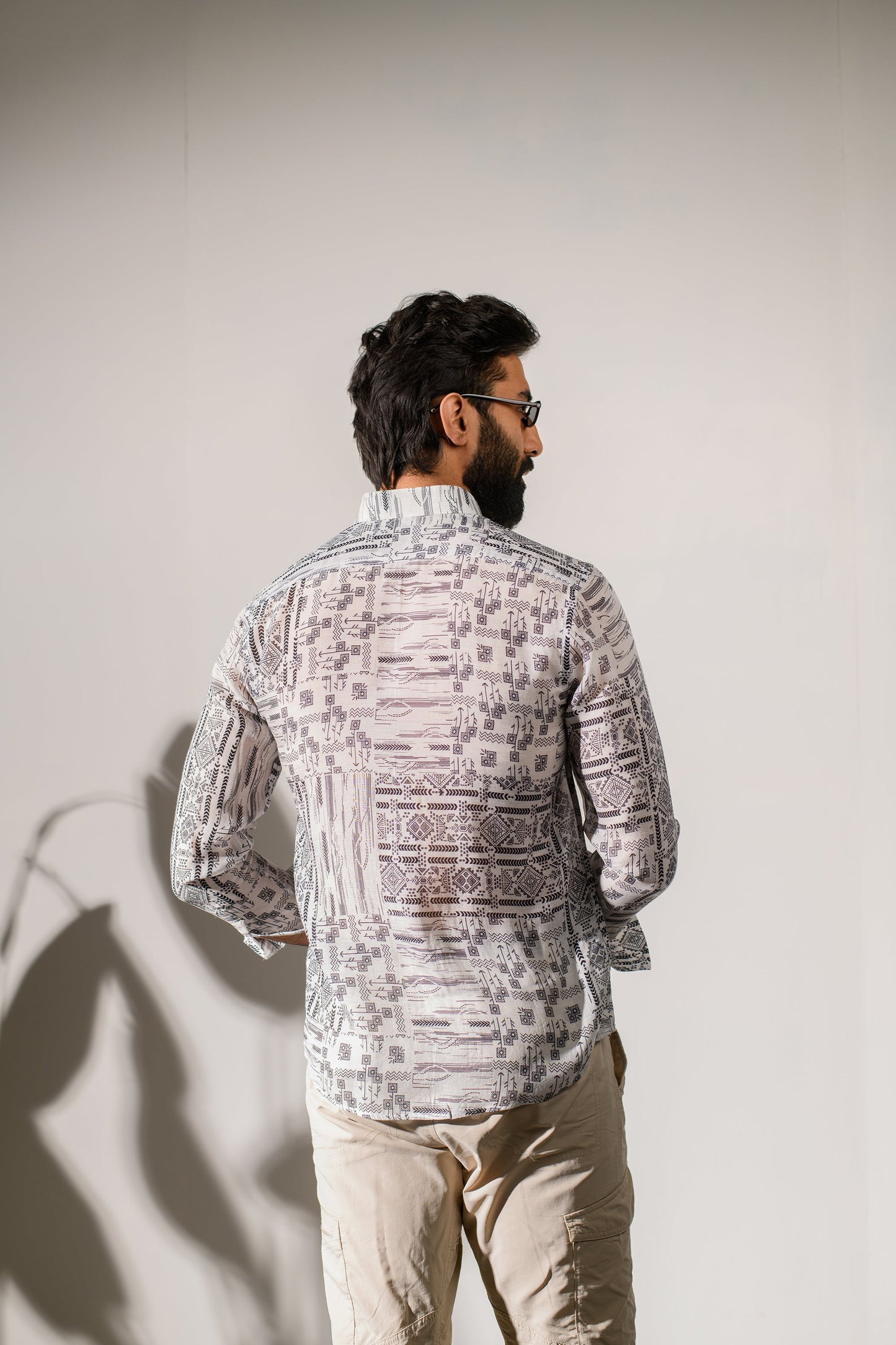 Back view of a man wearing a boho white silk shirt for men with intricate patterns