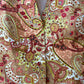 Close up of vintage paisley print jacket fabric in warm peach beige red and olive floral motifs