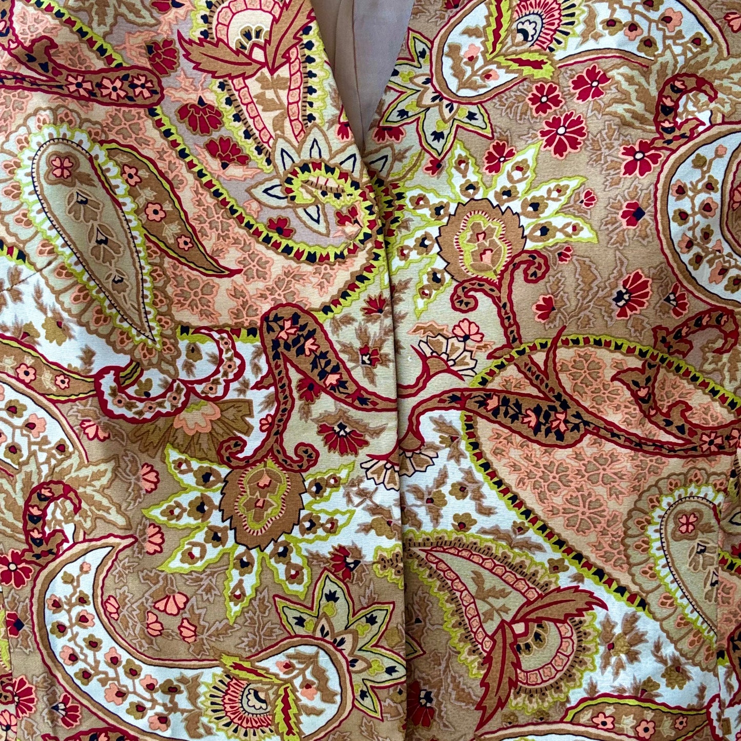 Close up of vintage paisley print jacket fabric in warm peach beige red and olive floral motifs