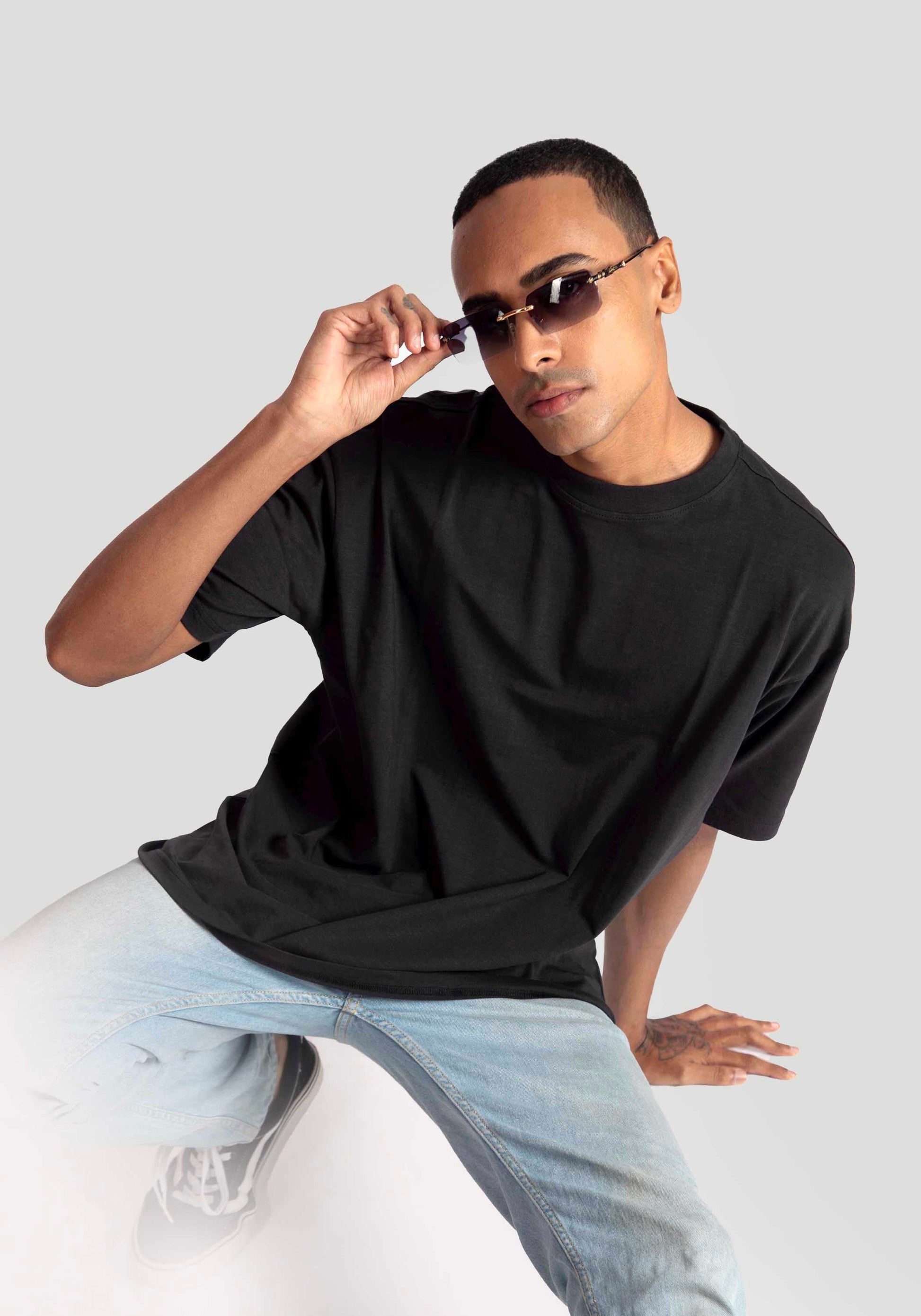 Model wearing Stylera Lifestyle charcoal black oversized t-shirt paired with light blue jeans and sunglasses
