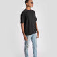 Man wearing charcoal black oversized t-shirt paired with light blue jeans and black sneakers