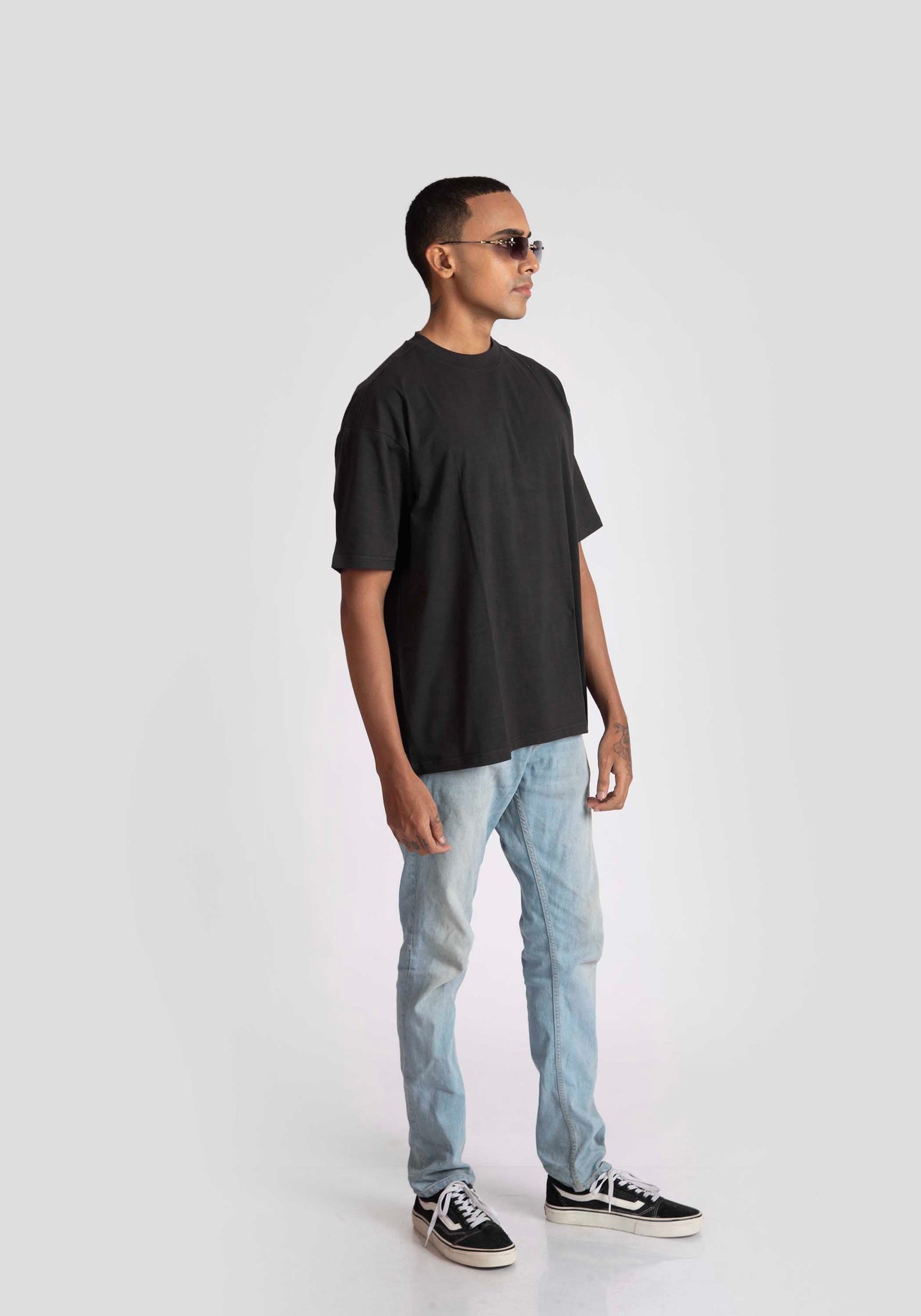 Man wearing charcoal black oversized t-shirt paired with light blue jeans and black sneakers