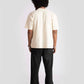 Back view of male model wearing Stylera cyberpunk oversized t-shirt in cream with black pants